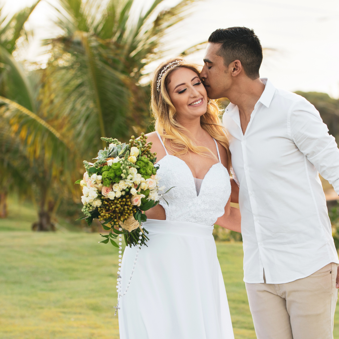 bride with flowers next to groom kissing her on the head