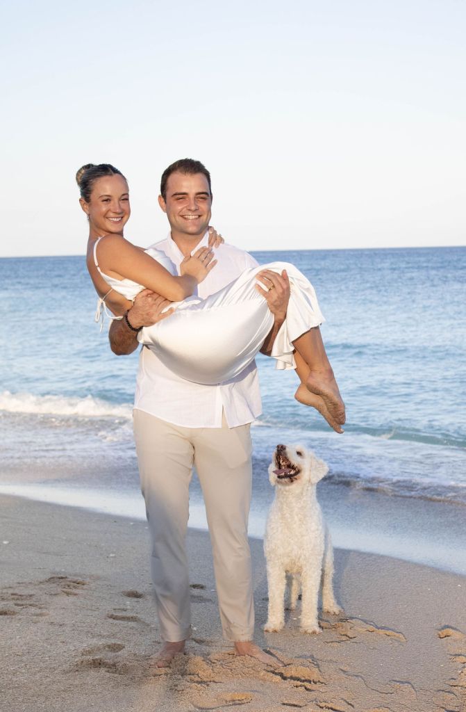 man carrying a woman while their dog is watching at Delray Beach 